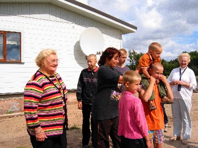 Pildil: Helju Salumets (esiplaanil) ja Helgi Sooaru (taga) koos pereema Marget Pihu ja viie pojaga kaheksast uue maja ees. Foto: Tiina Sarv  - pics/2005/11144_1.jpg