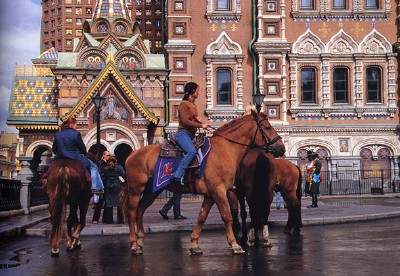 By the Gribojedov Canal, St. Petersburg. Vladimir Balabnev, 2003, colour photo, 29 x 44 cm. The photographer described how the girls became cross after he captured this shot and surrounded him with their horses, demanding money for having their picture taken. His escape ended up costing 6 times 100 roubles.<br><br>Behind the posse, the multicoloured Cathedral of the Resurrection of Christ (also known as the Church on the Spilled Blood), stands in jarring contrast to its Baroque and Classical surroundings. Ordered built by Tsar Aleksandr III in 1883 to reflect a “truly Russian” style as opposed to “contaminating Western influence” (St. Peterburg’s raison d’etre), it stands on the spot where his father, Tsar Aleksandr II was assassinated in 1881. - pics/2005/9677_2.jpg