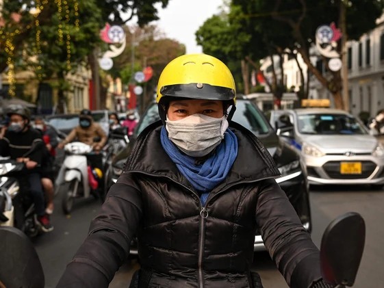 A woman wearing two face masks to prevent the spread of COVID-19 waits at a traffic light in Hanoi on Jan. 29, 2021, a day after Vietnam recorded its first coronavirus outbreak in almost two months. Photo by MANAN VATSYAYANA/AFP via Getty Image - pics/2021/02/57939_001.jpg